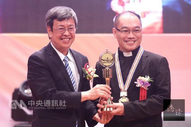 副總統陳建仁（左）23日在台北出席「第27屆醫療奉獻獎頒獎典禮」，頒發個人醫療奉獻獎表揚投入醫療教育不遺餘力、高齡百歲的神父賴甘霖，由神父裴育聖（右）代為領獎。（中央社提供）