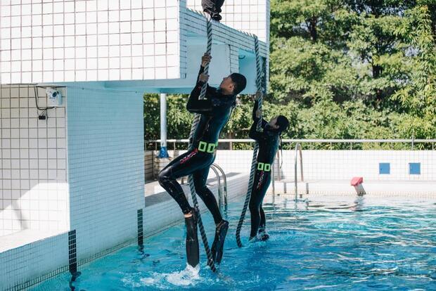 任毅、任婕共同抓繩索攀登上跳台。