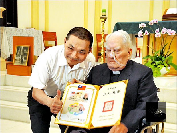 新北市副市長侯友宜頒發台灣身分證給梅冬祺神父（右）。（自由時報提供）