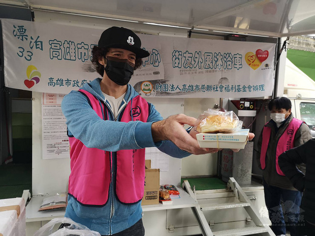 來自澳洲的36歲兼職攝影師夏宇星(左)12日頂著寒風,在高雄市社會局及高雄市慈聯社會福利基金會三民街友中心幫忙下,拿著熱食、暖暖包及衣物給街友,他自願成為志工,服務街友付出奉獻。