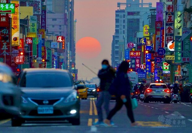 高雄市青年路「懸日」美景近日再度現身,橘澄澄的太陽緩緩落下,以車水馬龍的街道與五光十色的招牌為襯,格外吸睛,也吸引許多攝影愛好者前往搶拍。