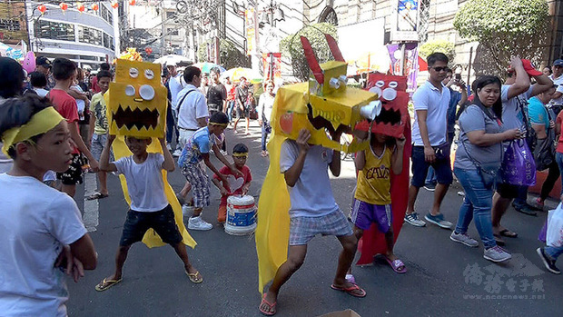 菲律賓孩童以水果箱作頭、水杯為眼，自製獅頭，克難表演舞獅。