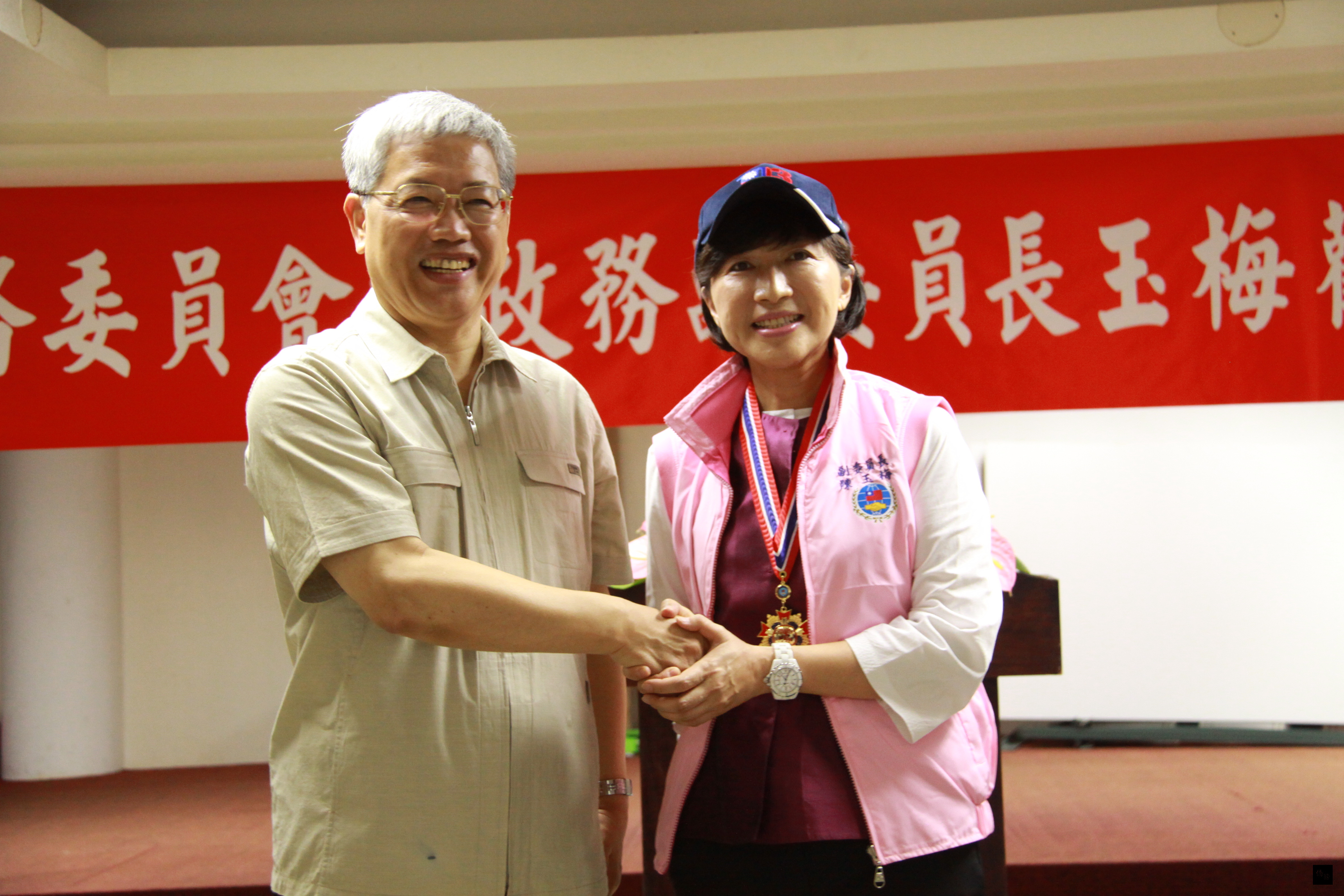 僑委會委員長陳士魁（左）致贈志工帽及志工背心給副委員長陳玉梅（右），希望她能夠做永遠的僑務志工。