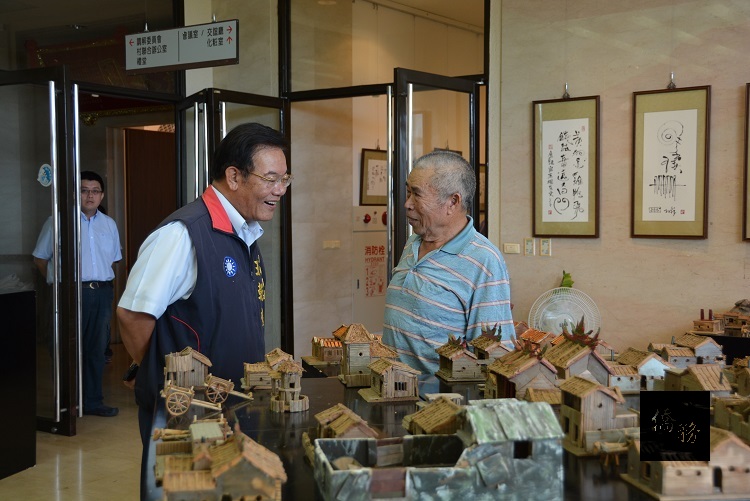 素人藝術家蔡樹木(右)在新屋古厝系列展開幕茶會中,向澎湖縣長王乾發(左)說明創作理念。(澎湖縣政府提供)