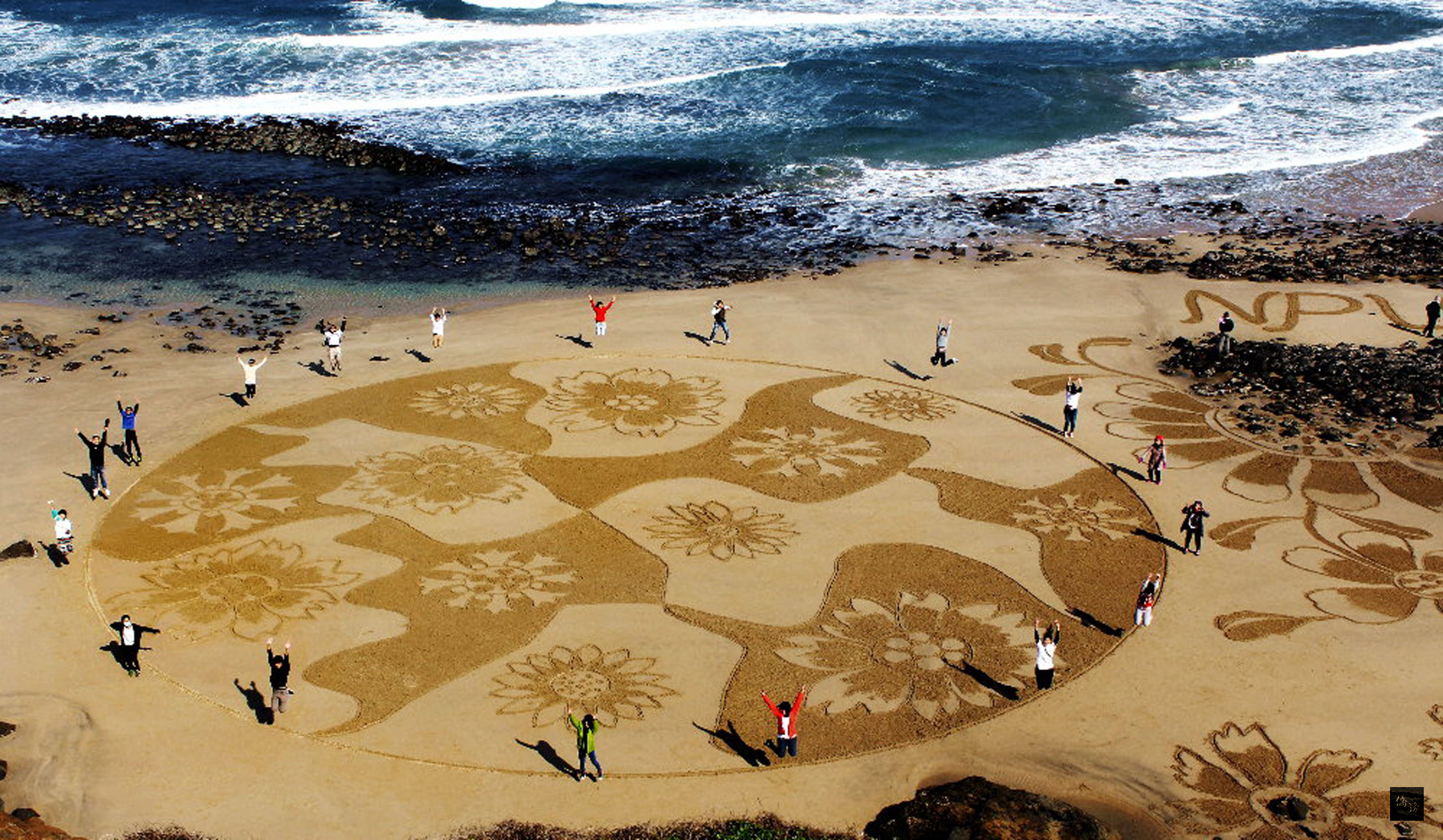 國立澎湖科大與澎湖在地迎風藝術群藝術家，13日趁著退潮之際，在澎湖內垵休憩園區的沙灘上集體完成「沙灘上的夢想」沙景藝術創作。（中央社提供）