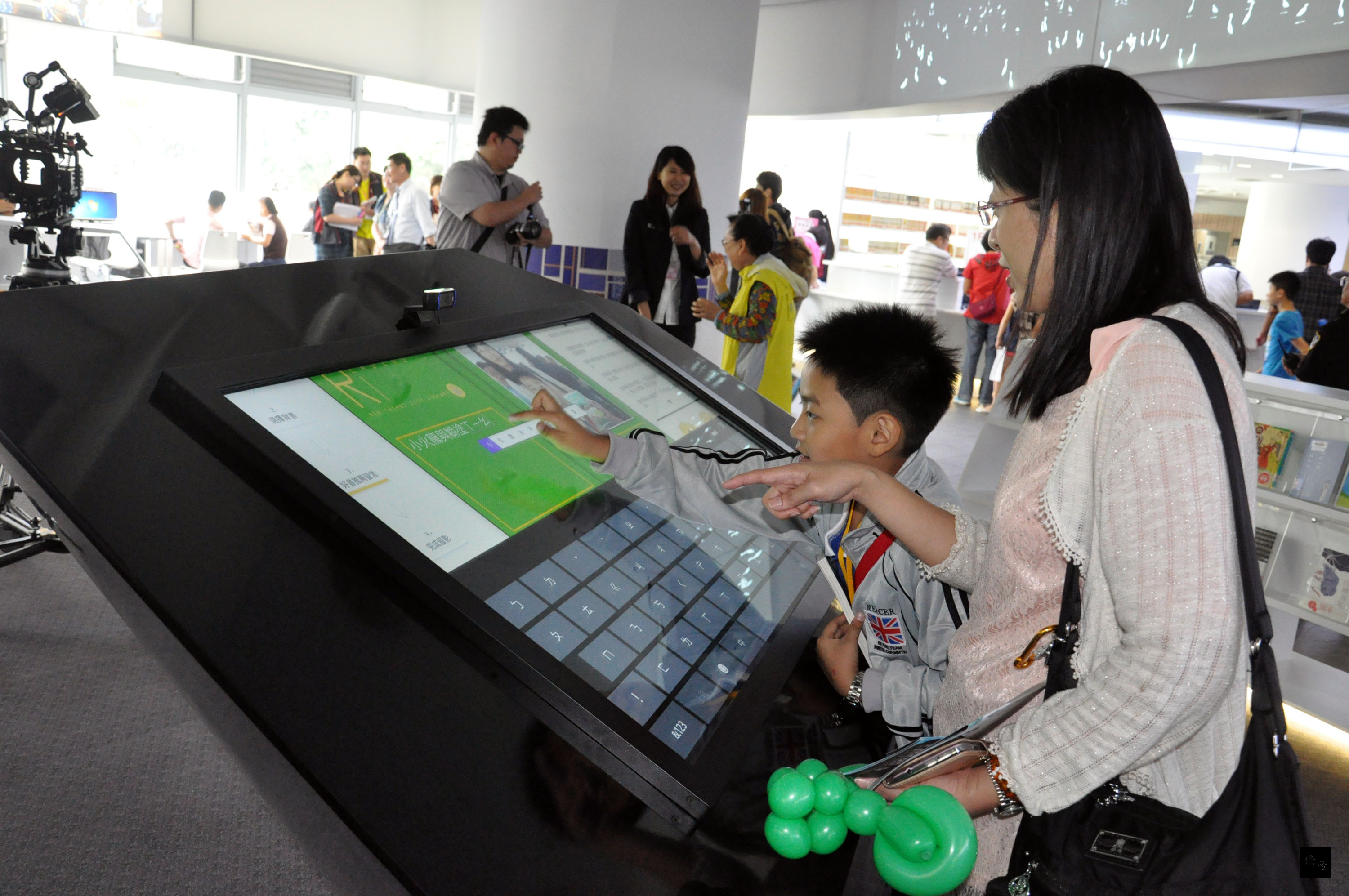 新北市立圖書館10日開館試營運,這座圖書館將成為全台第一座供民眾24小時閱讀的圖書館。許多人一早湧進館內,搶先體驗能互動的「好書推薦大頭拍」。(中央社提供)