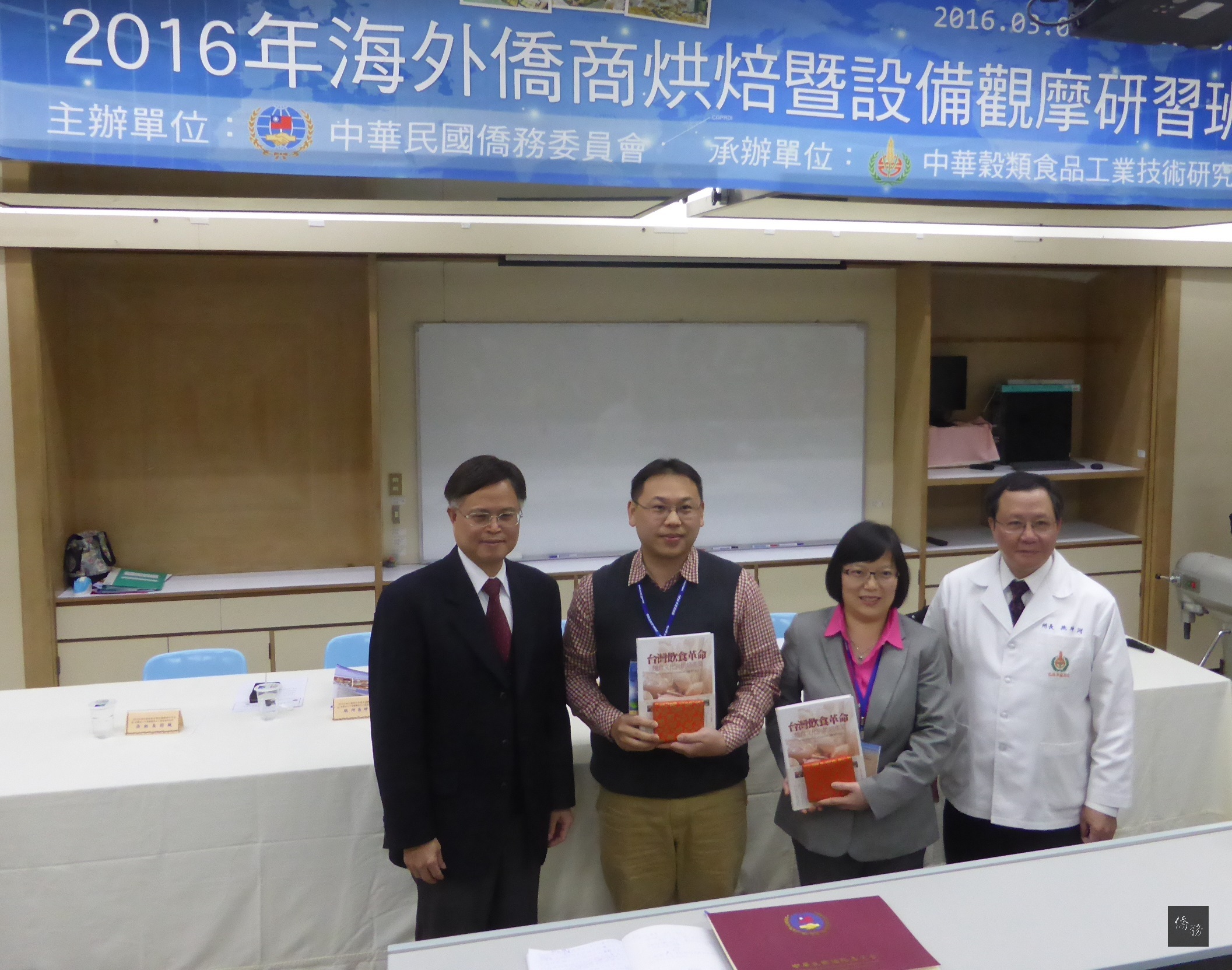 僑務委員會2016年海外僑商烘焙暨設備觀摩研習班在中華穀類食品工業技術研究所舉行結業式暨成果發表會。僑委會僑商處處長林瑞隆（左一）、學員長沈佳鴻（左二）、副學員長陳維倩（右二）、中華穀類食品工業技術研究所所長施坤河（右一）合影。