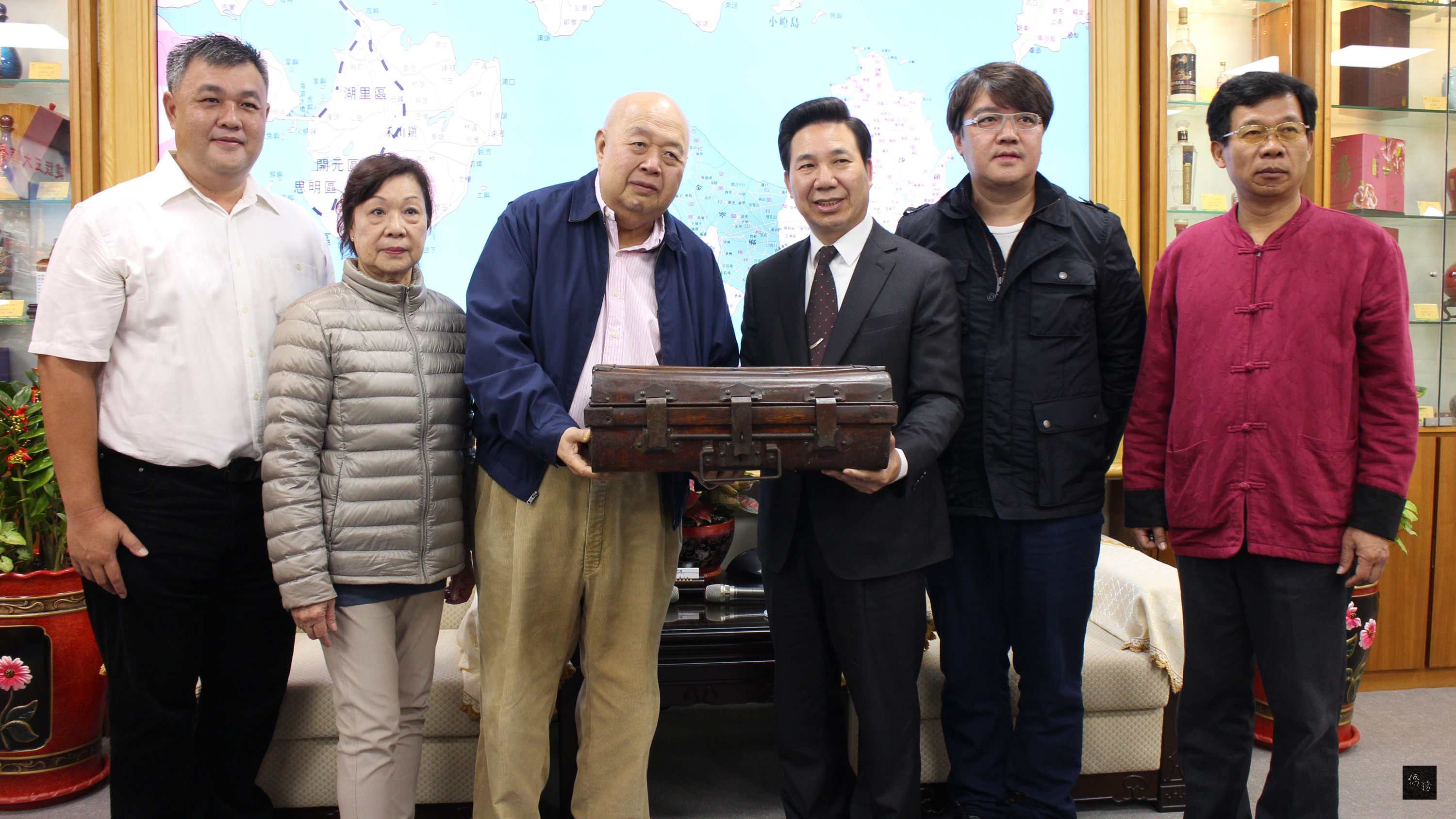 旅居馬來西亞的金門僑民吳梓新(左三)捐出先人吳心泉落番使用的鐵箱給金門縣長陳福海(右三),內有吳心泉宅地契;陳福海允諾全力維護古宅,活化再利用。(中央社提供)