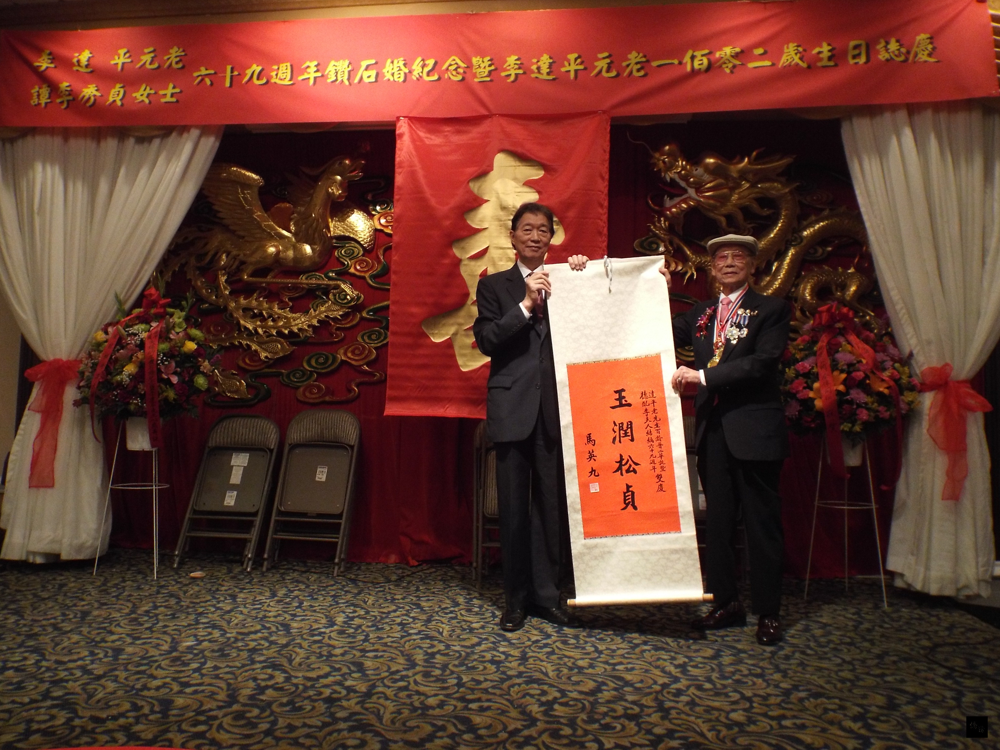 駐美代表沈呂巡(左)代表致贈總統馬英九「玉潤松貞」賀軸給美京中華會館元老李達平(右)。(華府僑教中心提供)