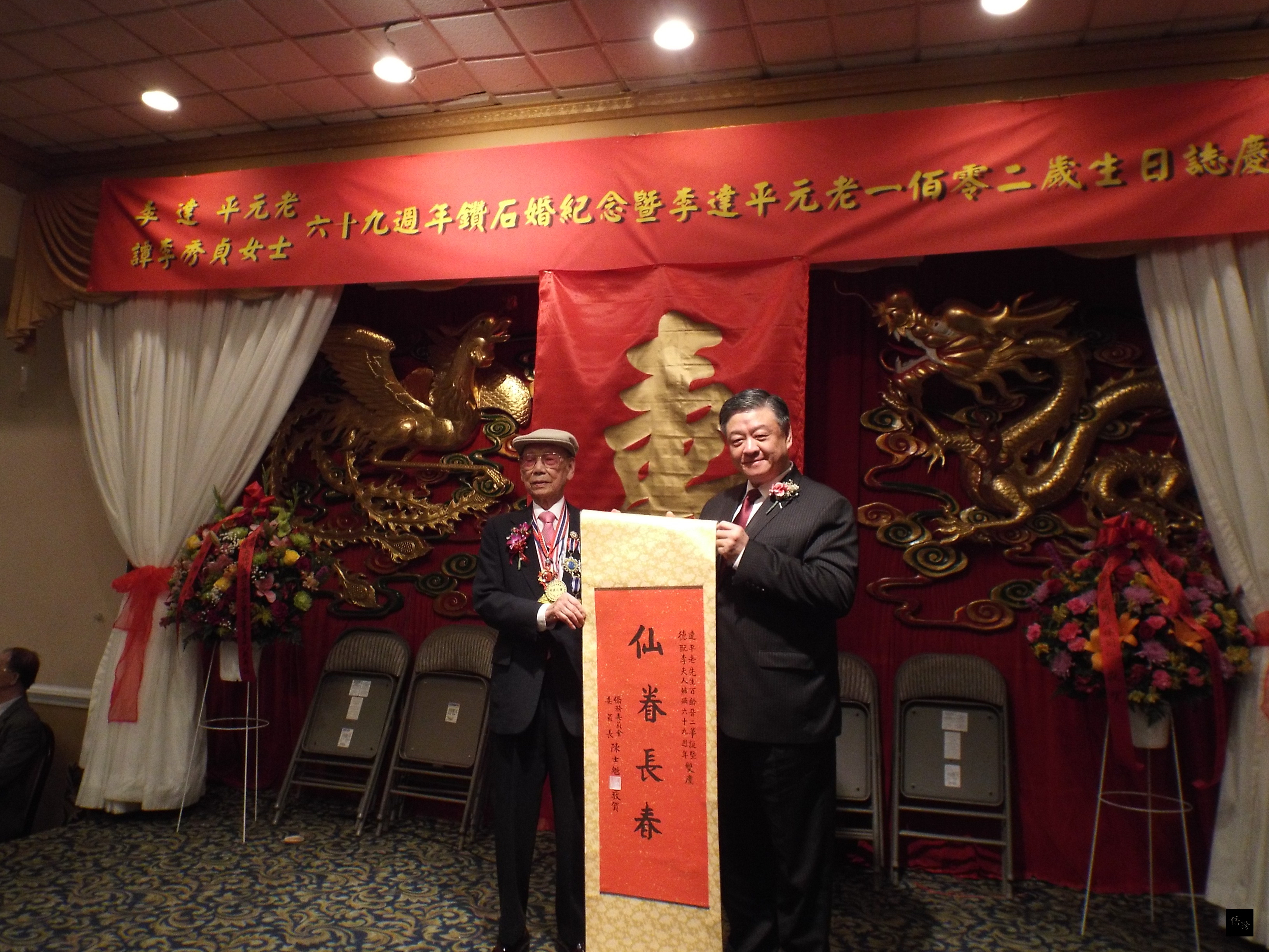 僑務委員會副委員長呂元榮(右)代表致贈「仙眷長春」賀軸給美京中華會館元老李達平(左)。(華府僑教中心提供)