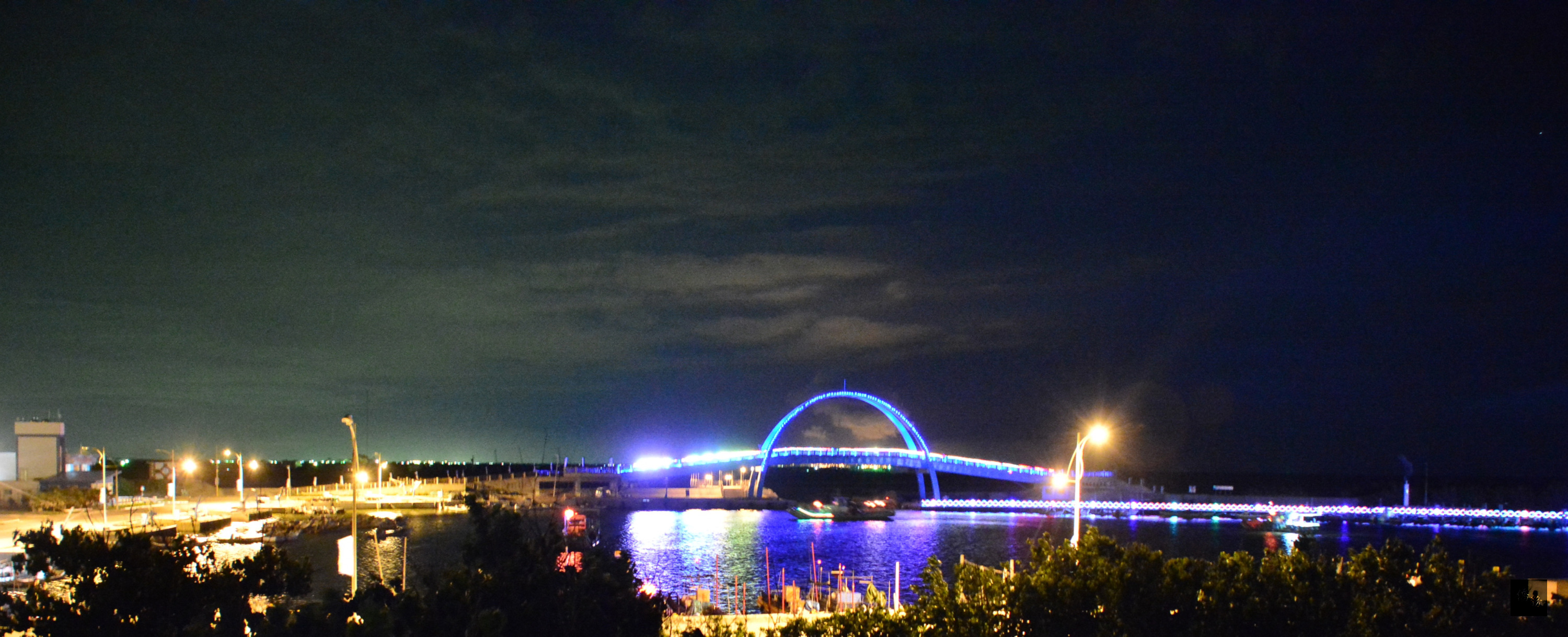 彰化芳苑鄉的王功漁港，到了晚上，王者之弓橋上炫爛的燈光，點綴夜空。（中央社提供）