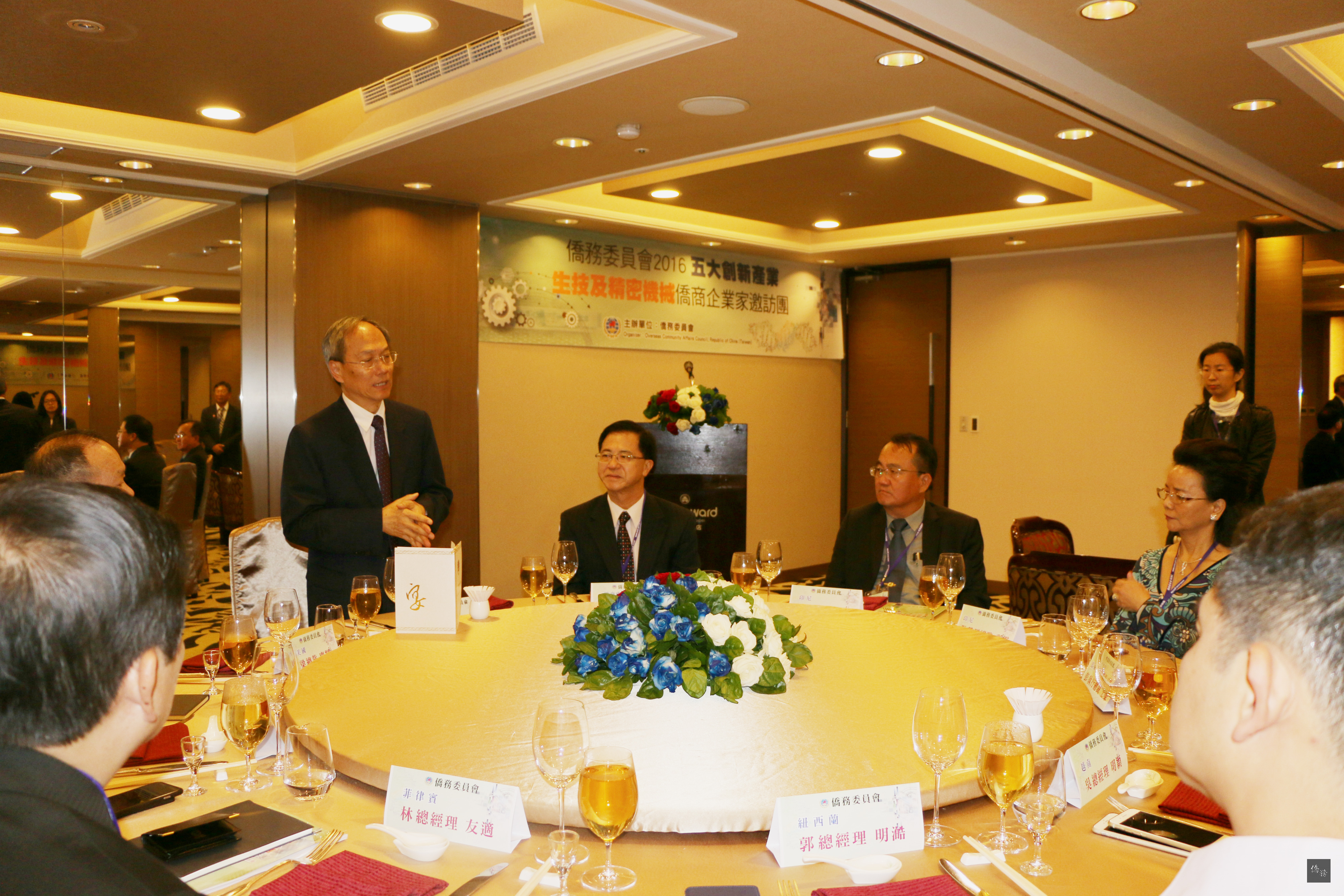 僑務委員會委員長吳新興（左立者）與8名受邀返國參訪、具生醫及精密機械背景的僑台商餐敘，勉其在五大創新產業中找尋合作商機，以振興台灣經濟。