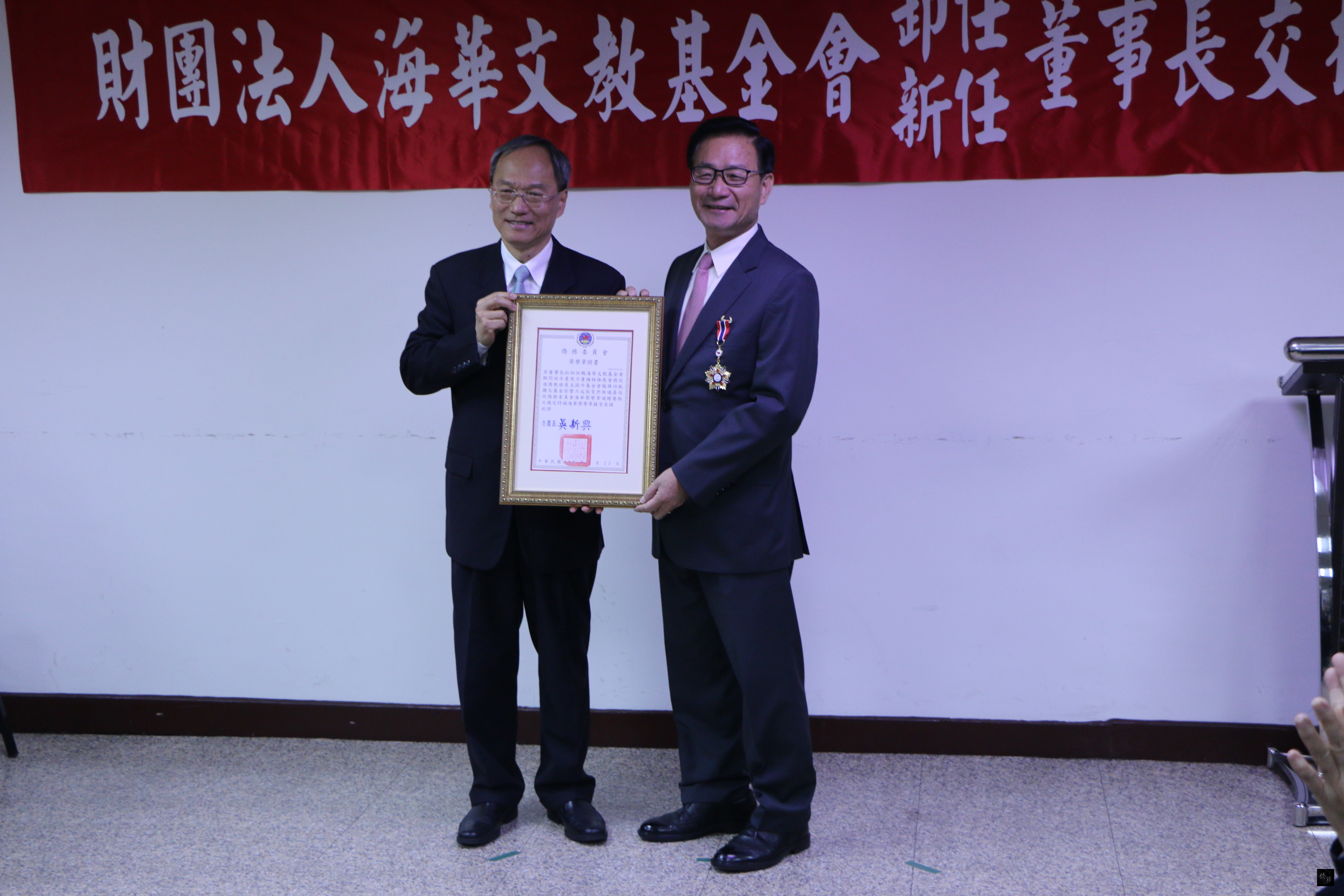 僑務委員會委員長吳新興（左）頒發海華榮譽章予吳松柏（右），表揚他提升基金會服務功能及擴大影響力的貢獻。