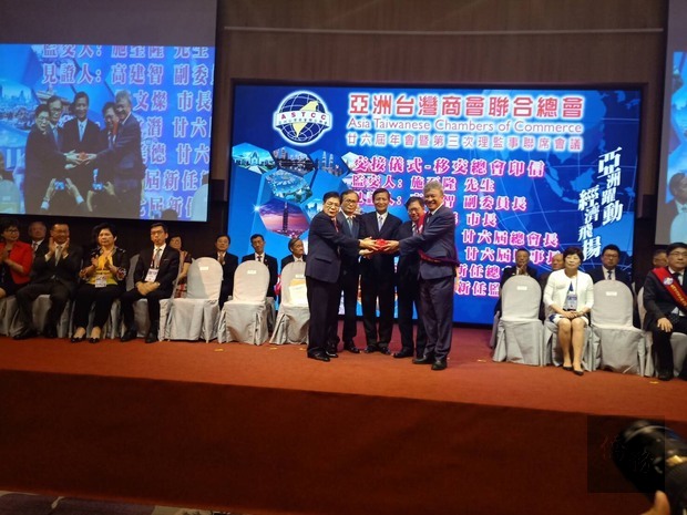 在高建智(中)的見證下,亞洲台灣商會聯合總會總會長移交印信。