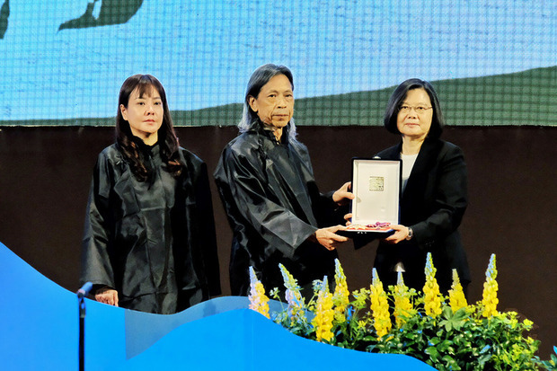 「台灣文學之母」鍾肇政追思音樂會14日在桃園市龍潭國小舉行,總統蔡英文(右)出席並頒發一等景星勳章及褒揚令,由鍾肇政的兒子鍾延威(中)及媳婦蔣絜安(左)代表接受。(中央社提供)