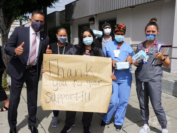 洛杉磯台美商會13日捐5萬片口罩給洛杉磯社區醫院（Los Angeles Community Hospital）。醫護人員出門相迎，拿手寫的海報致謝。