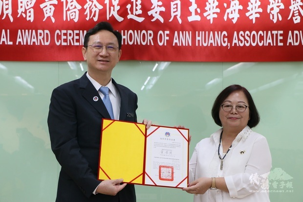 僑委會委員長童振源(左)頒贈海華榮譽章證書予黃玉華。