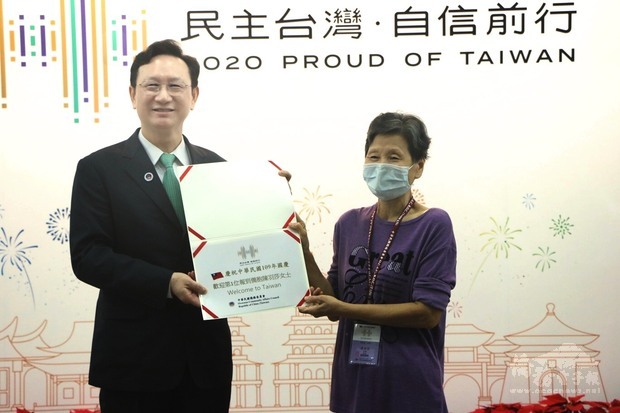 僑委會委員長童振源(左)致贈證書予首位報到僑胞陳羽莎(右)。