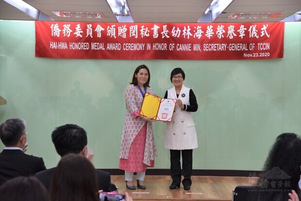 徐佳青（右）代表委員長童振源頒發海華榮譽章及證書給閔幼林（左）。