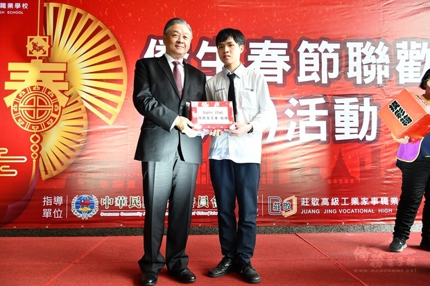呂元榮(左)贈僑委會摸彩禮品給獲獎僑生