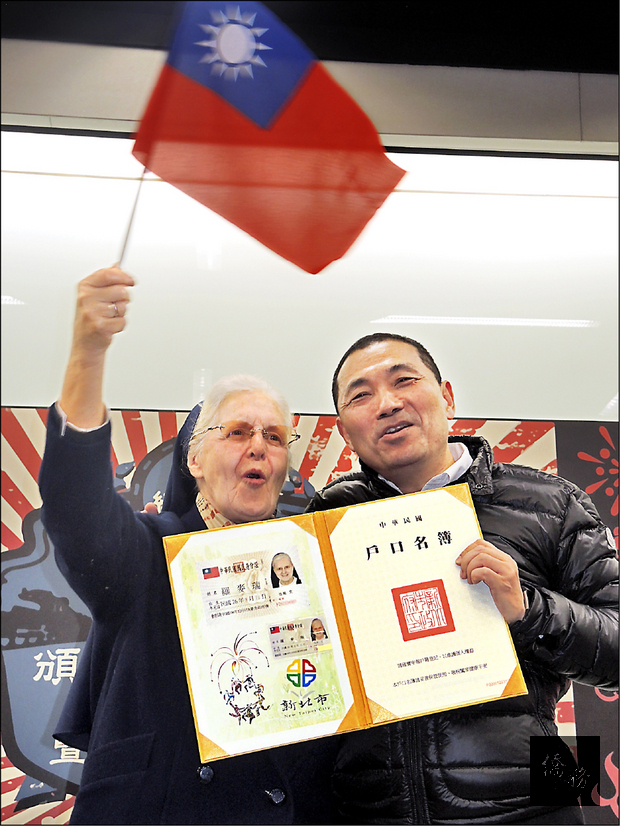 羅麥瑞（左）從新北市副市長侯友宜手中領到中華民國身分證，成為台灣公民，開心手揮國旗。（自由時報提供）
