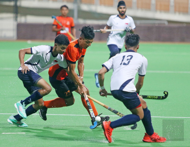 桃園市體育會曲棍球代表隊在新加坡移地訓練,13日與新加坡國家代表隊友誼賽,圖為桃園市代表隊黃柏雄(左2)面對新加坡包夾,仍奮勇突圍,爭取進攻機會。