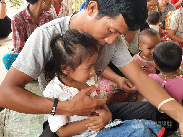 台北醫學大學飛洋國際服務團今年8月到柬埔寨進行為期2週的偏鄉衛教，發放體溫計並教導當地人量體溫/中央社提供