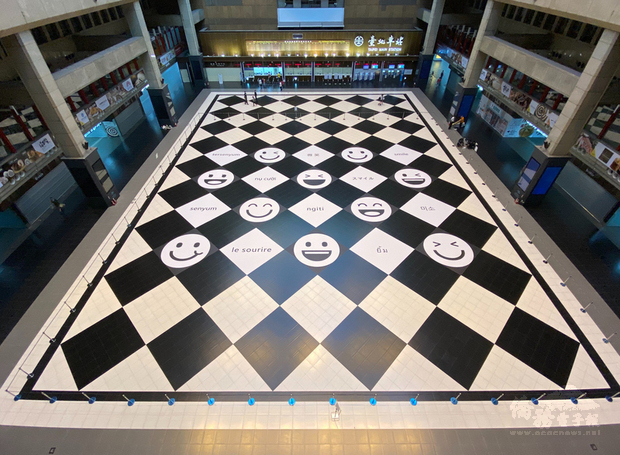 台鐵曾一度考慮禁止民眾在台北車站大廳席地而坐,引發爭議,台鐵後來廣納各方意見,在北車大廳增加微笑地貼及寫著「微笑」的10種語文,展現友善與包容。(台鐵提供)