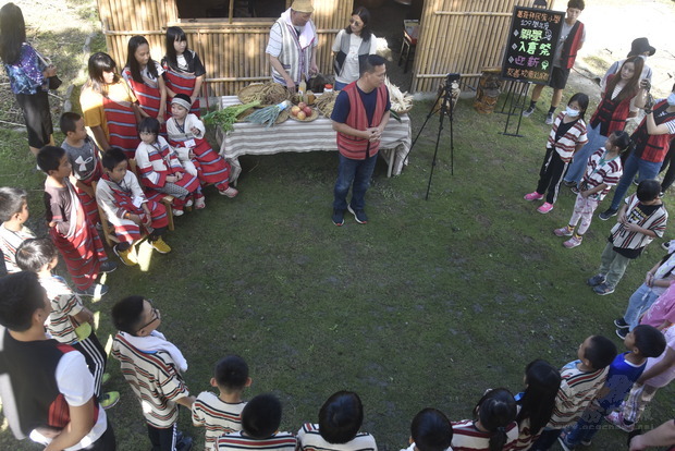 全校師生共同圍繞在泰雅傳統建築旁，期望泰雅文化代代傳承。