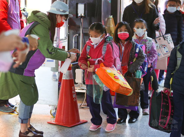 台北市吉林國小22日開學，學生上午進入校園前，先排
隊用酒精消毒雙手，落實防疫工作。