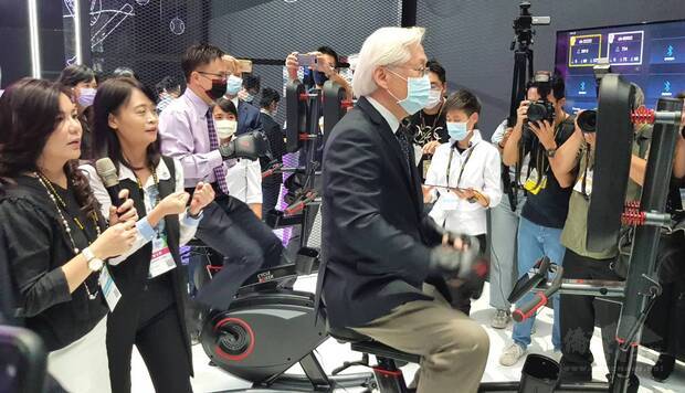 科技部部長吳政忠（右起）、外貿協會董事長黃志芳、中小企業處副處長蘇文玲，在明躍國際執行董事王絢臻介紹下，體驗拳擊腳踏車的沉浸式連線競賽。（經濟部提供）