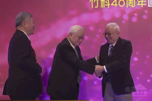竹科歡慶40周年並頒發傑出貢獻獎。聯電榮譽董事長曹興誠(右)主動與台積電創辦人張忠謀(中)握手致意,成多年來兩人不但首次同台也是「首握」。(竹科管理局直播畫面)