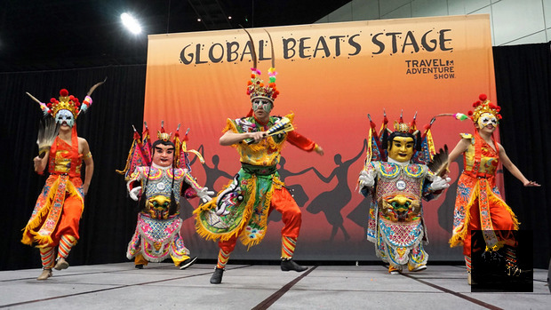 全美規模最大的洛杉磯旅展16日開幕，代表台灣的三太子與陣頭舞者在表演舞台，配合董事長樂團「眾神護台灣」歌曲混搭演出。（中央社提供）