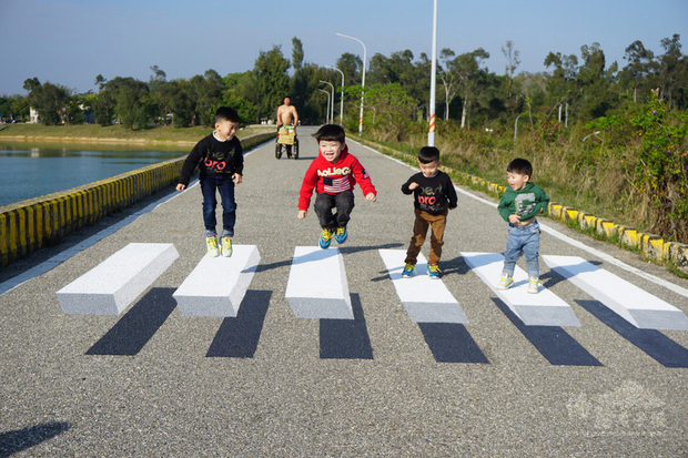 金門縣漂浮斑馬線位於金湖鎮中正公園內,太湖淨水廠旁的壩堤上,創作者是廖駿杰和陳詩薏,不少民眾慕名而來,爭相站在最佳拍攝點搶拍打卡,小朋友也站在斑馬線上開心跳躍。(中央社提供)