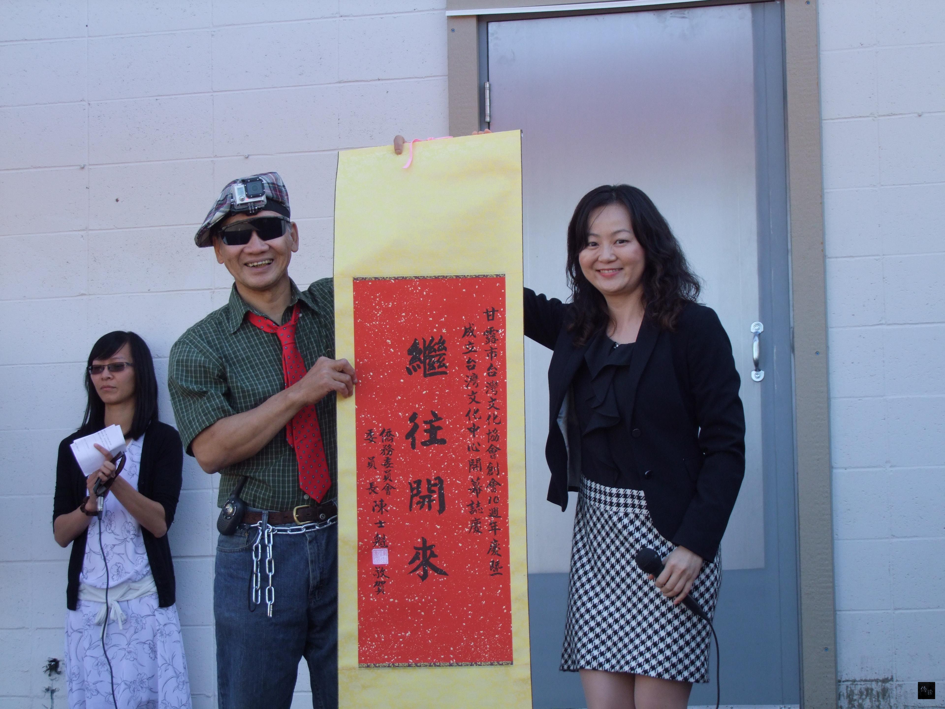 加拿大甘露市台灣文化協會舉辦創會10周年慶暨台灣文化中心開幕典禮,駐溫哥華辦事處僑務主任楊修瑋(右)轉致僑委會委員長陳士魁題贈的賀軸給會長李光生(左)。(駐溫哥華辦事處提供)