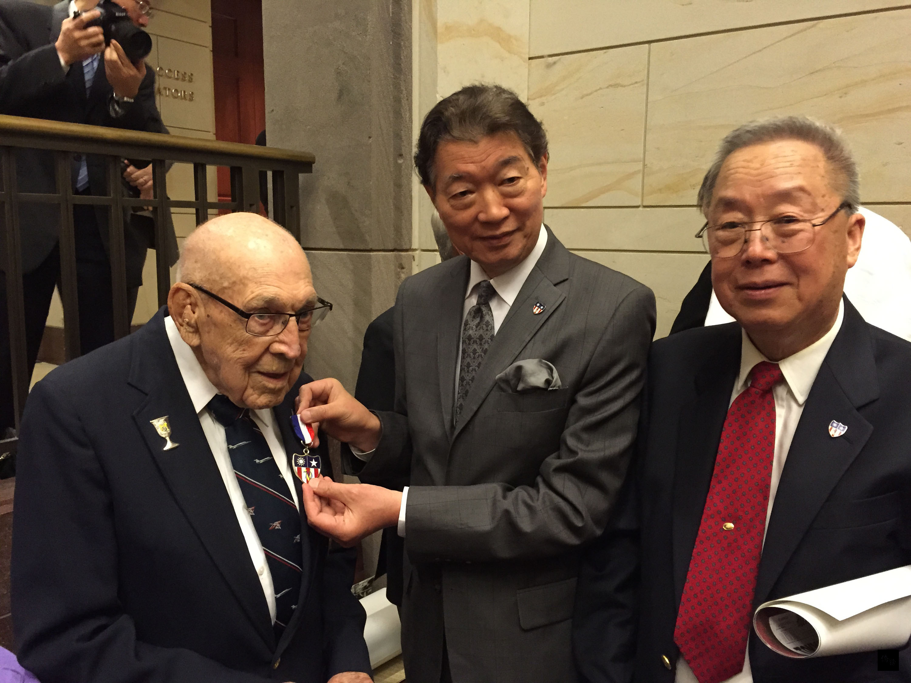 駐美代表沈呂巡在18日國會山莊杜立德紀錄片首映會中，致贈參與東京空襲的老兵柯爾（左）徽章。（中央社提供）