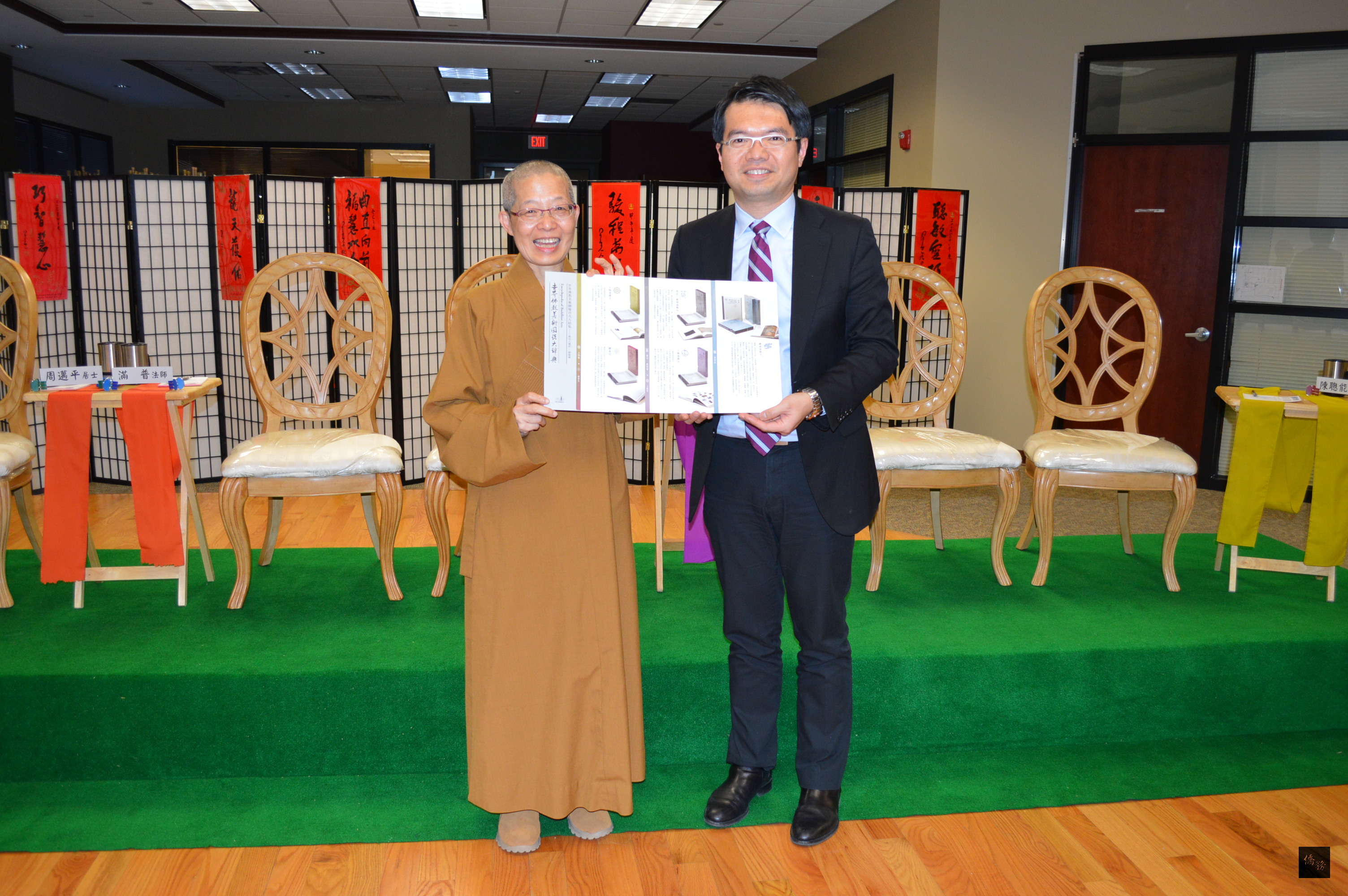 國際佛光會芝加哥協會舉辦讀書心得發表會，佛光山芝加哥禪淨中心監寺滿普法師（左）贈送「世界佛教美術圖說大辭典」20冊套書給芝加哥僑教中心主任王偉讚（右）。（芝加哥僑教中心提供）
