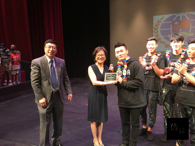 僑務委員譚逸心(左起)、僑務促進委員陳可徵向福爾摩沙馬戲團導演陳冠廷致贈感謝獎牌。