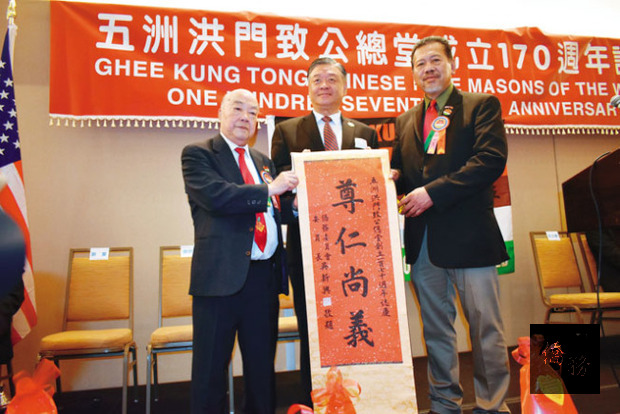 中華民國僑務委員會副委員長呂元榮(中)向五洲洪門致公總堂贈送委員長吳新興親筆題詞「尊仁尚義」,會長黃煜錚(左)和盟長趙炳賢(右)接收。/世界日報提供