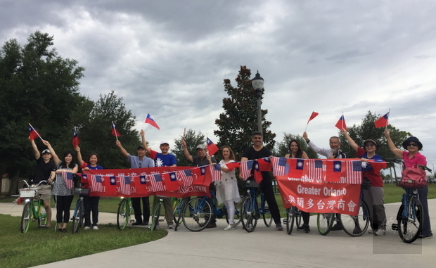 奧蘭多議員奧提茲(右六)、中佛州僑界人士與陳敏先(右四)騎單車遊美國公園,開心揮舞國旗。(世界日報提供)
