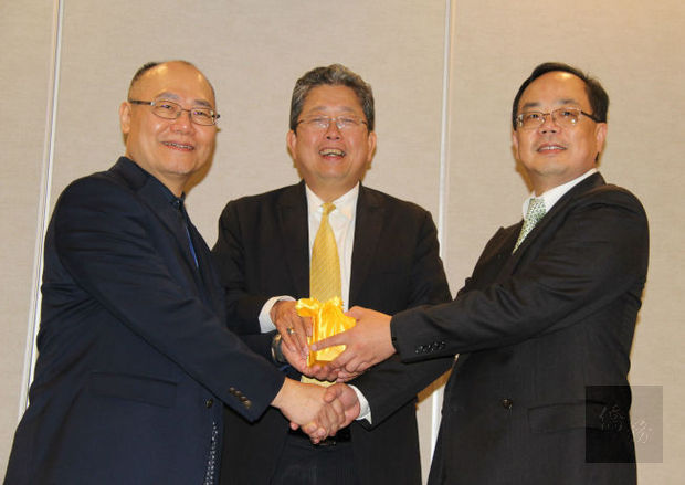 中華學人學會會長交接印璽,由劉孟周(左)交予朱子宇(右),中為劉經巖。(世界日報提供)