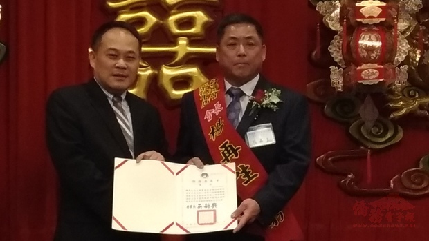 黃敏境（左）代表僑委會委員長吳新興，頒發賀狀予新任會長楊再生(右)。