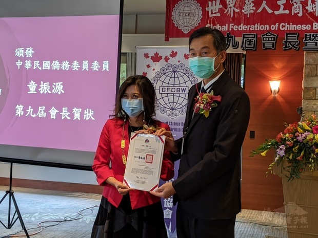 陳剛毅（右）代表僑委會委員長童振源頒發賀狀予周素蓮（左）。