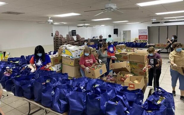 義工們分裝包括蔬果與牛奶、冷凍肉品等準備發放的食物袋。（世界日報提供）