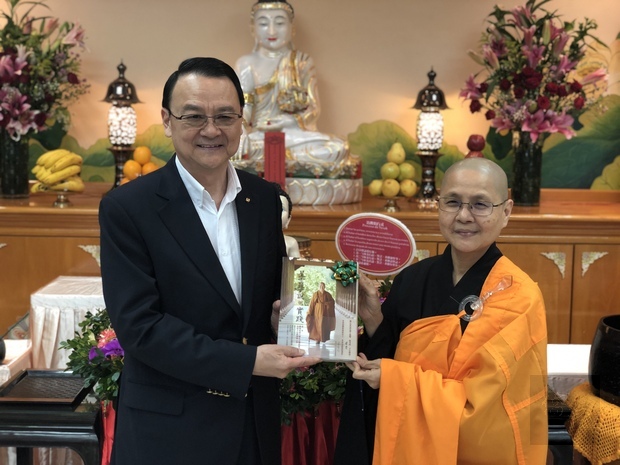 覺文法師致贈結緣品「星雲學說與實踐」一書予周麟。