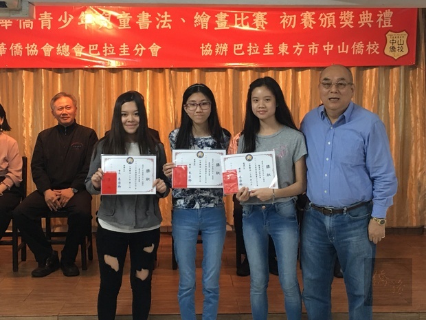 華僑協會總會巴拉圭分會會長朱榮卿 (右) 親自為巴拉圭書法繪畫比賽各組前三名頒發獎狀和獎金。