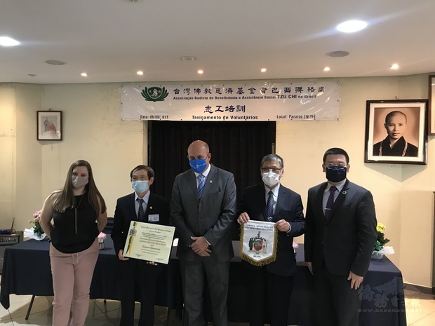 在詹前校(右1)等人見證下，陳守永(左2)、林合省(右2)共同代表臺灣佛教慈濟基金會巴西聯絡處接受聖貝爾納多杜坎普市榮譽社團證書及錦旗，為巴西僑團增進國民外交之典範。
