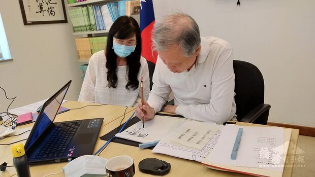 陳新苗(右)在鏡頭前示範隸書的寫法。