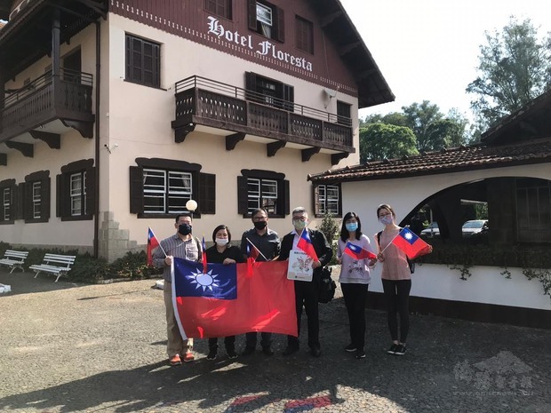 詹前校(左1)、周世鴻(右3)等人到訪僑民張炳快(左3)、陳秀倫(左2)夫婦經營的旅館Hotel Floresta，合影時手持國旗共同祝賀光輝雙十。