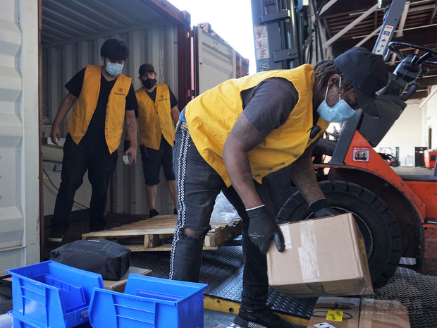洛杉磯疫情未解之下，台灣僑胞創立的幫幫忙基金會照常做公益，志工戴著口罩把物資裝滿貨櫃，準備送到加勒比海島國聖文森。